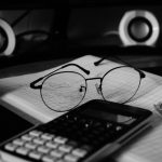 A computer desk with a keyboard, mouse and glasses on it